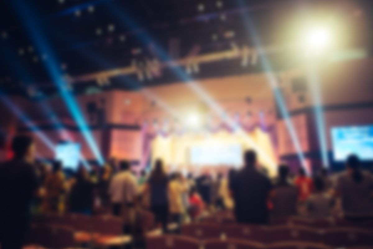 blurred of Christian congregation worship God together in big meeting room with music stage light effected, Christian background, praise and worship concept.